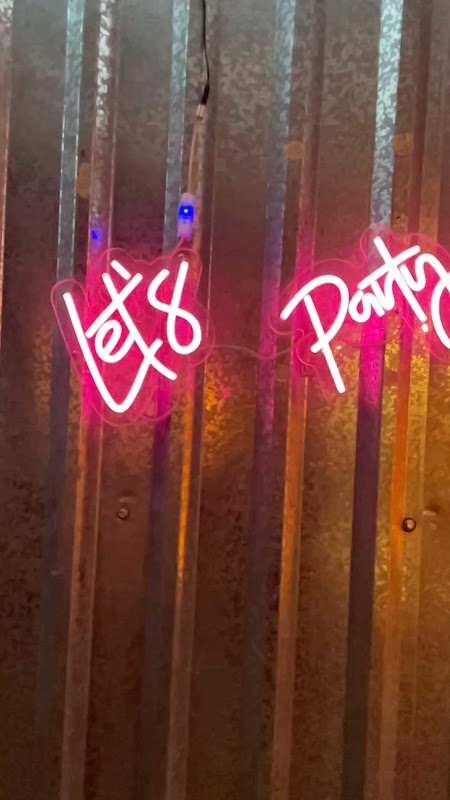 Frikk Factory con su barra de hamburguesas y luces nocturnas — vista interior con clientes y música de fondo