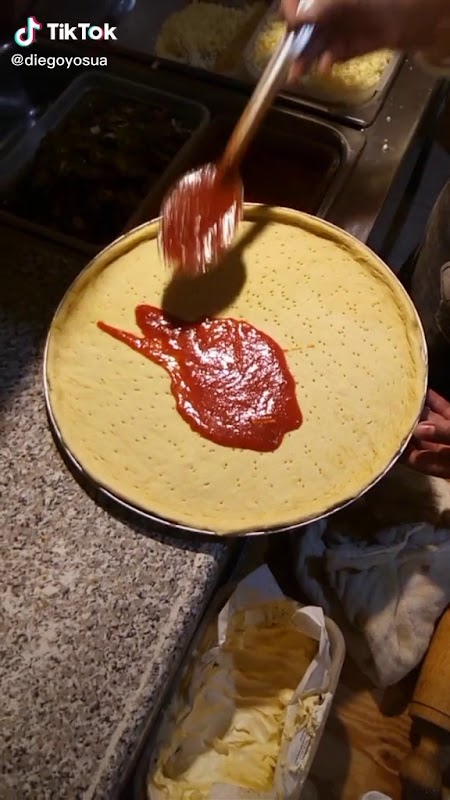 Liverpoolques — vaso de pulque curado con trozos de mango y guayaba, servido en tarro tradicional, con fondo de barra colorida