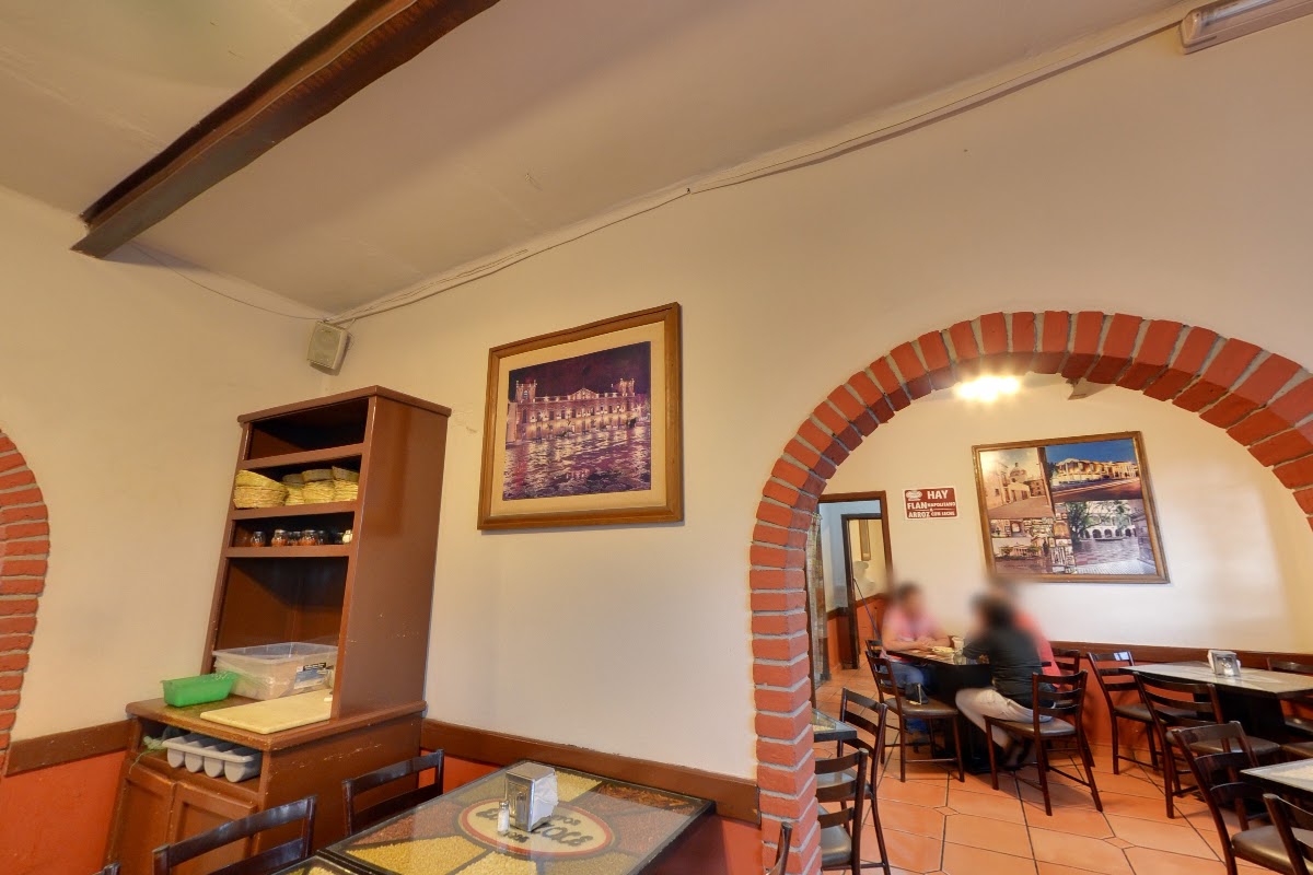 Interior con mesas de madera, clientes conversando y cervezas artesanales en Antojitos El Pozole