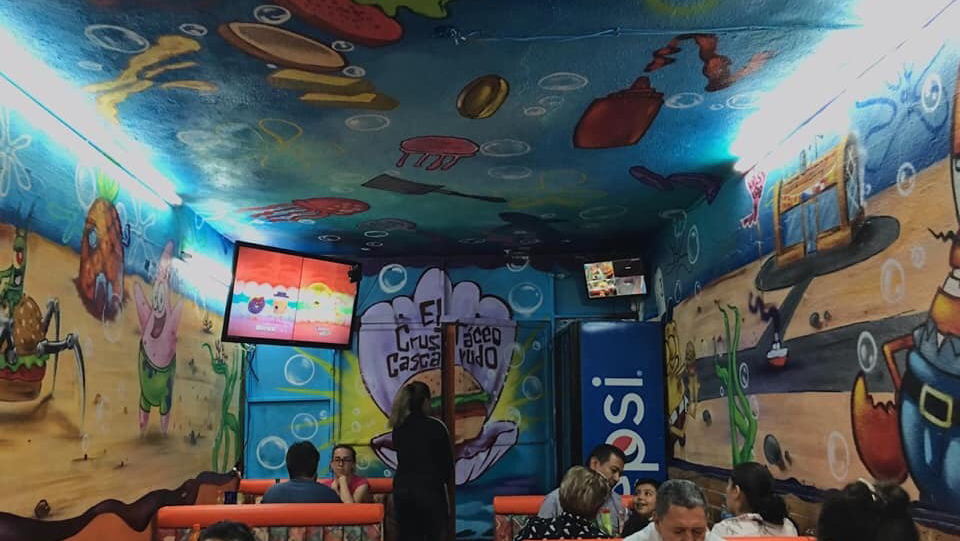 Interior del local con barra, salsas caseras y clientes compartiendo una mesa — enfoque en la atmósfera y el servicio