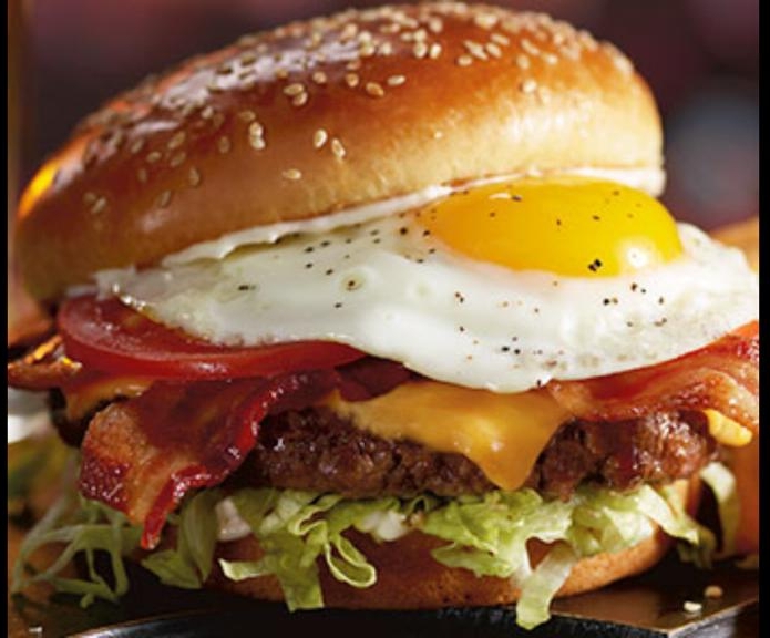 Hamburguesa BBQ de búfalo en primer plano, mostrando la salsa brillante y papas crujientes al lado