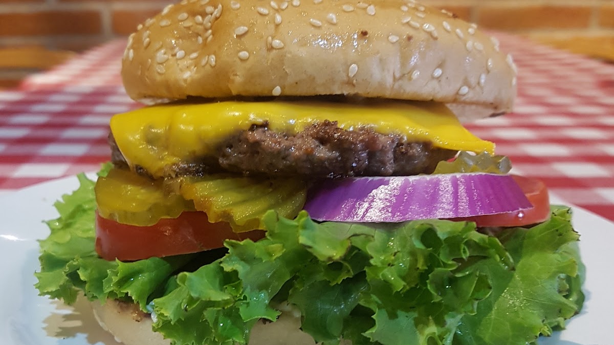 Plato del Buffalo Burger en Fatima's Grill SLP, con la hamburguesa jugosa, queso fundido, aros de cebolla crujientes y papas fritas al lado