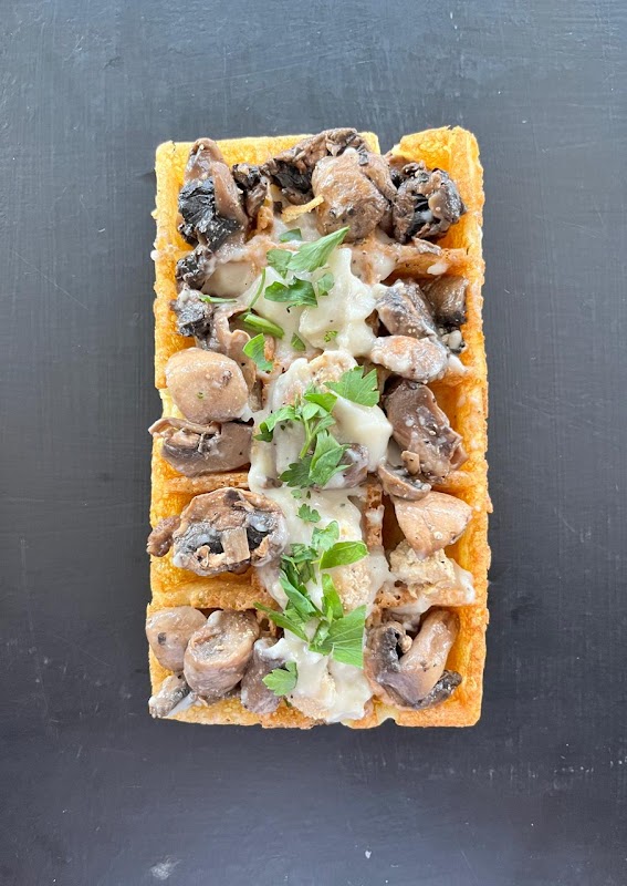 Primer plano de un waffle belga con crema, fruta fresca y sirope en Wafflessence de Paul — detalle del plato