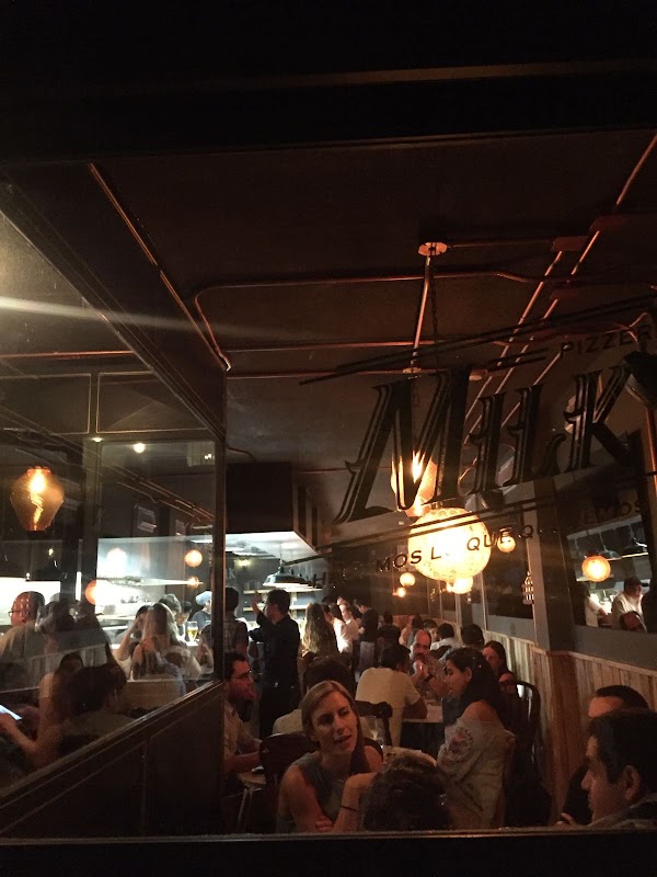 Vista del interior de Romito Pizzeria con horno de leña encendido y pizza Diavola recién salida, mostrando la masa inflada y el chorizo ahumado