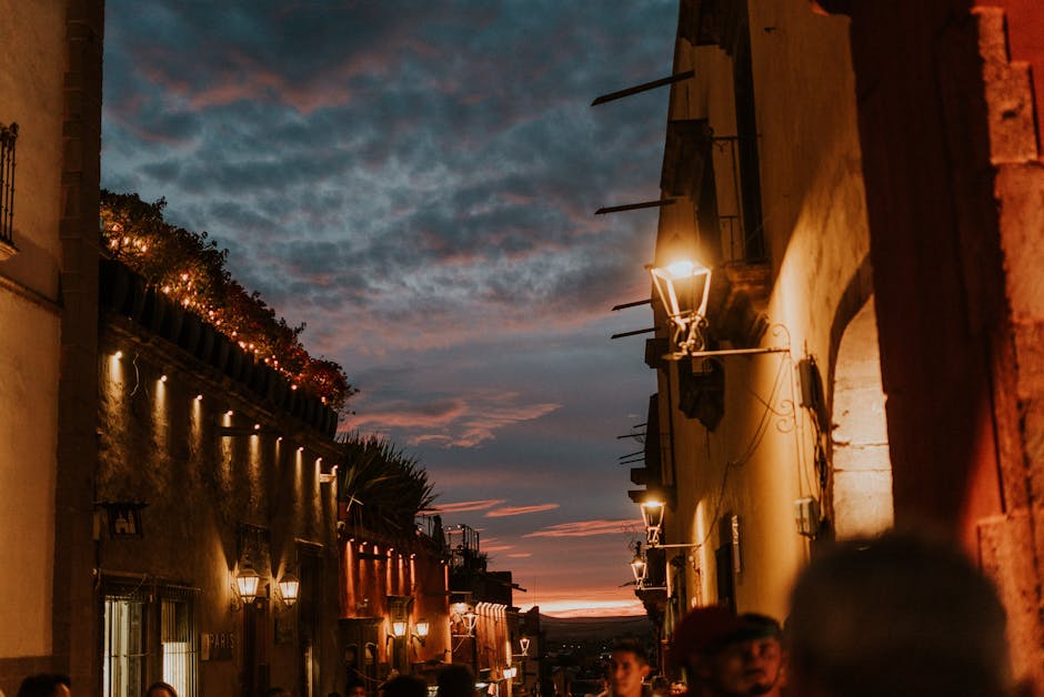 Enchanting urban street view at dusk with glowing lamps and sunset sky.