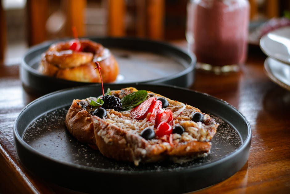A delectable pastry topped with fresh berries served on a dark plate in a cozy cafe setting.