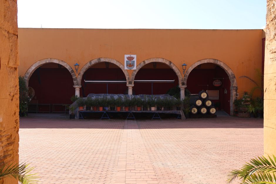 Arched courtyard in a historic Andalusian building with vintage wine barrels.