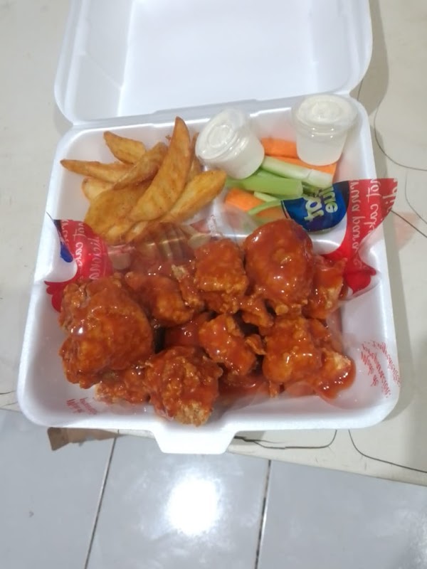 Alas de pollo crujientes con salsa picante en Cony Wings, servidas en una bandeja de madera