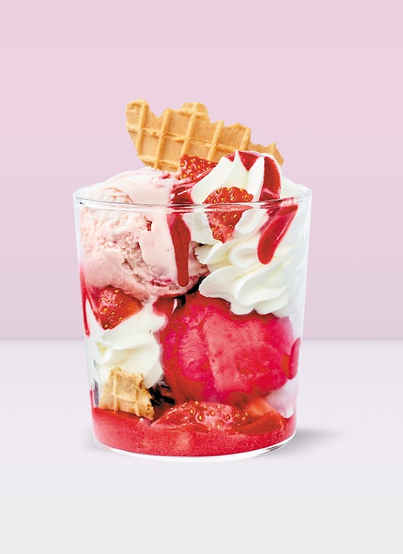 Copa de helado de fresa con trozos de fruta en Gelateria and Café Santa Clara – mostrada en la barra con café al fondo