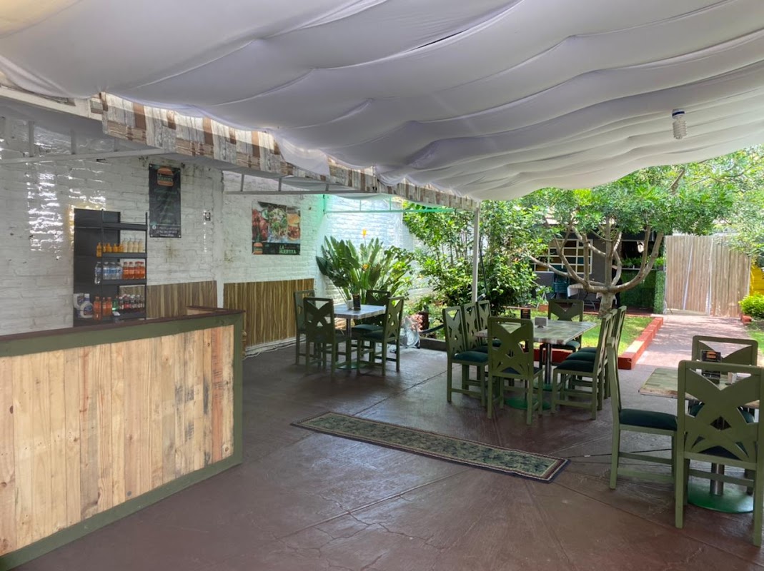 Interior de Bretes Bar, barra de madera, bartender preparando un cóctel de mezcal, luces de neón