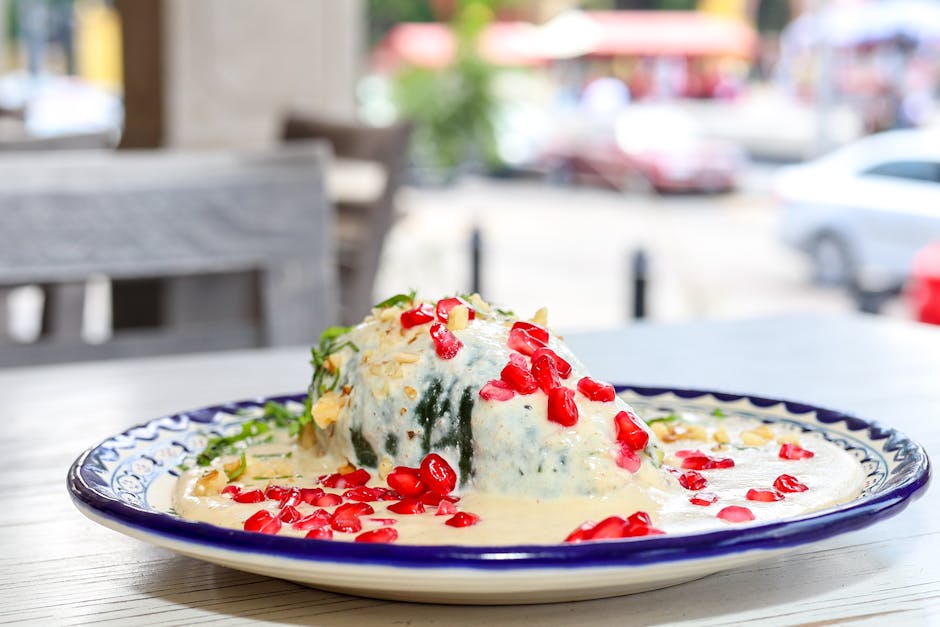 A traditional Mexican dish, Chiles en Nogada, garnished with pomegranate seeds and served on a colorful plate.