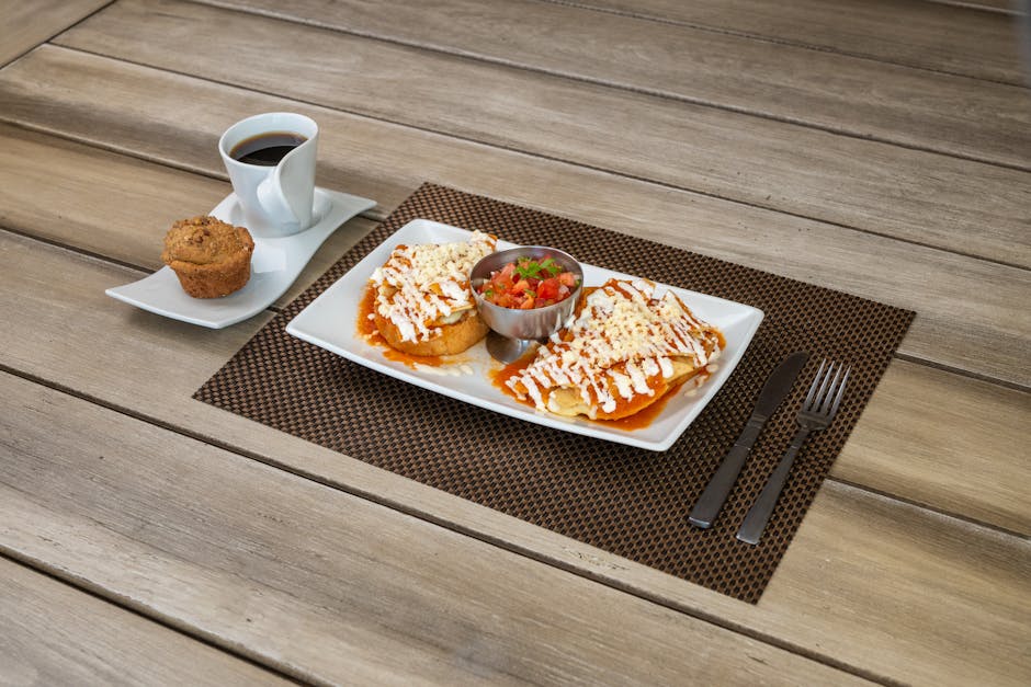 Delicious Mexican breakfast with enchiladas, salsa, coffee, and muffin at a restaurant setting.