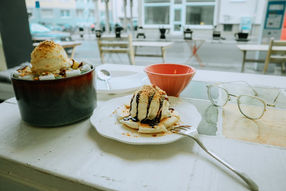 Close-up of a delicious dessert with ice cream, nuts, and chocolate syrup on a table.
