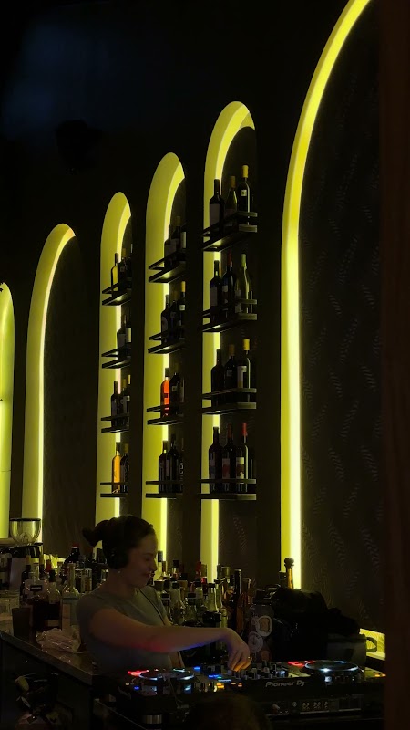 Interior del restaurante mostrando el horno de leña, paredes de ladrillo y mesas de madera, con clientes disfrutando