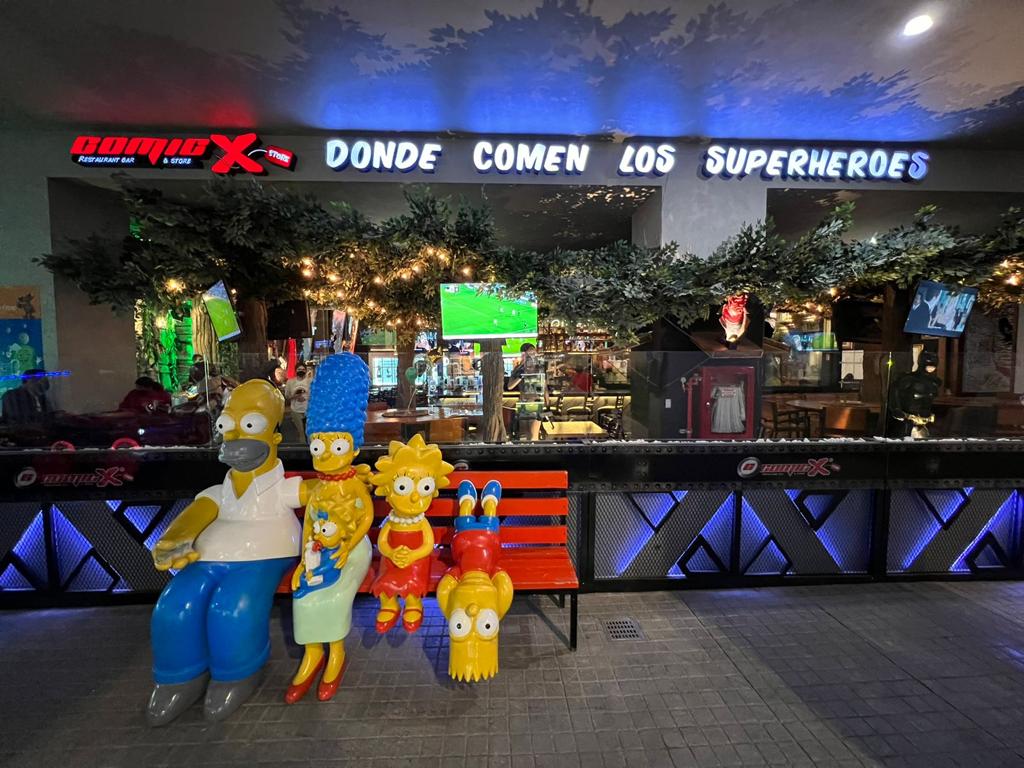 Interior de Comicx Otay en Alameda Otay, con decoración de cómics y barra llena de vasos — captura de ambiente geek