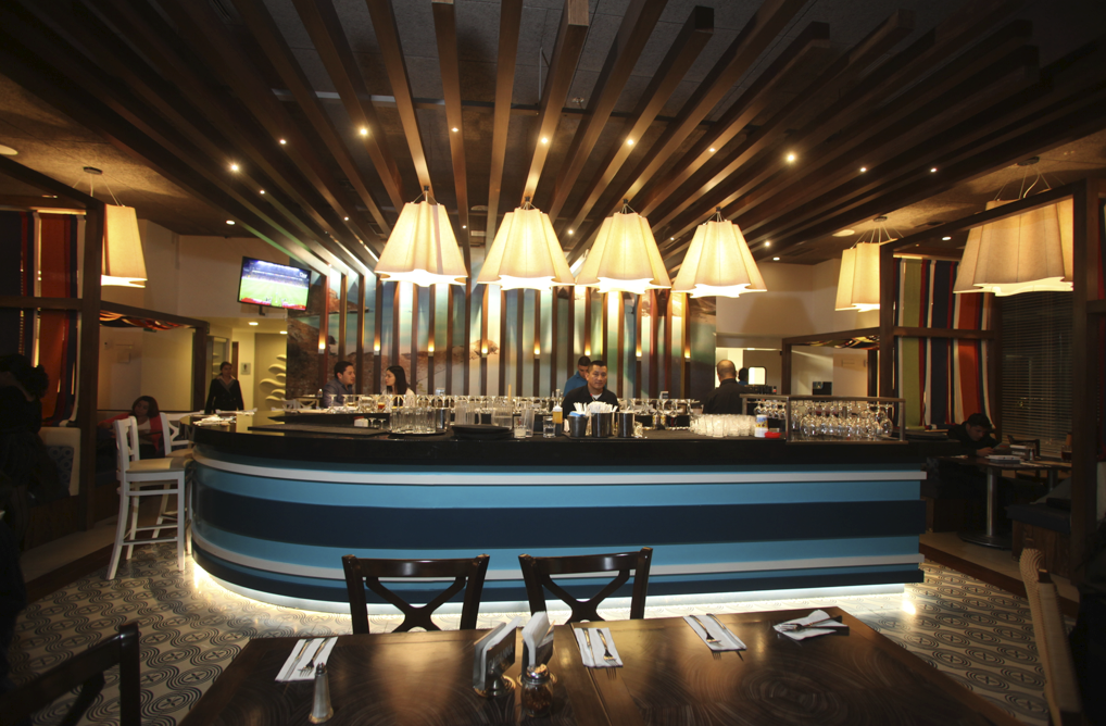 Interior de Cabanna Restaurant, mesas de madera y barra donde el chef prepara los platos