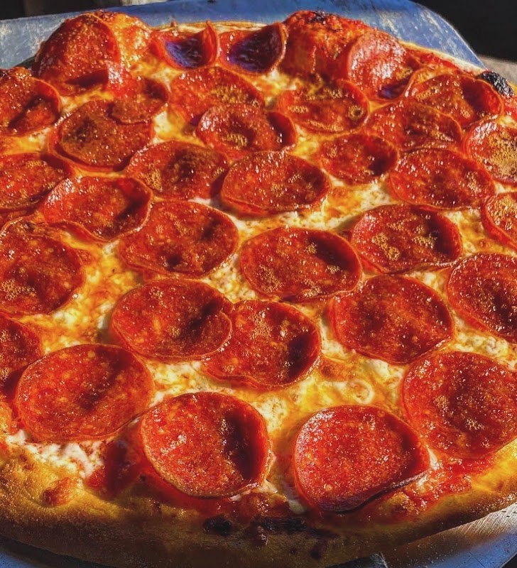 Pizza a la piedra en El Rincón, mostrando la base dorada y la sangría al lado, ambiente de terraza