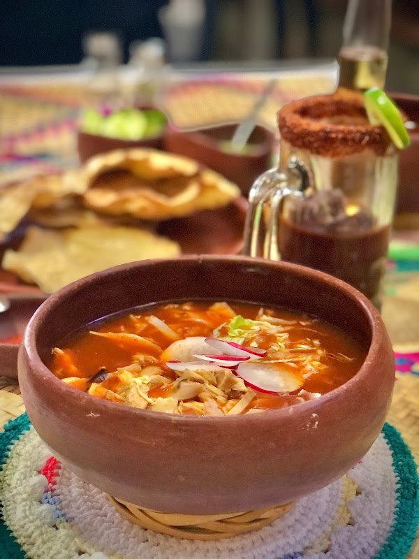 El Rincón Café Bar — interior con barra de madera, café humeante y una pizza de huitlacoche sobre la mesa
