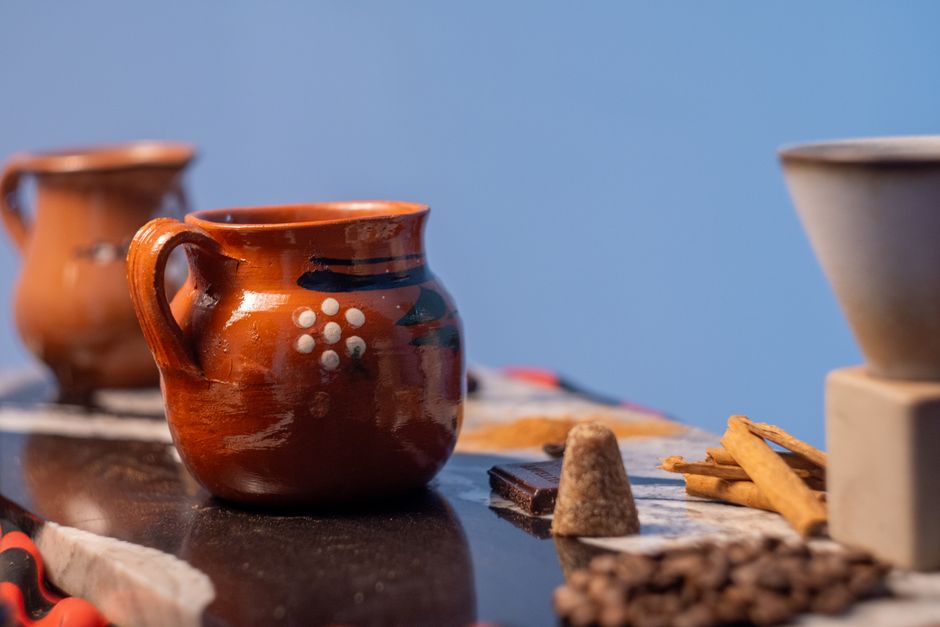 Close-up of traditional Mexican clay mugs with coffee and spices, showcasing cafe de olla.