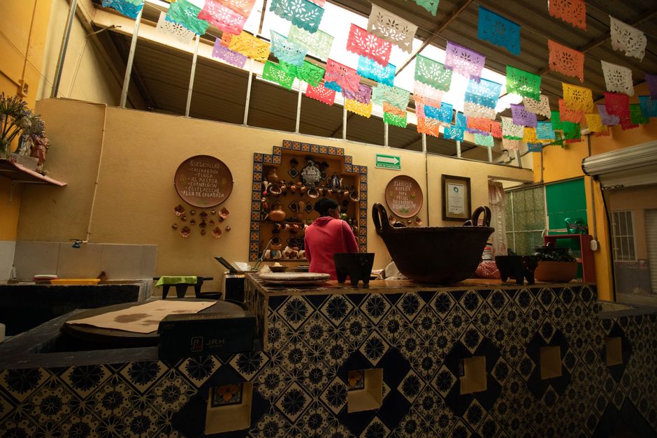 Traditional Mexican restaurant interior with colorful papel picado and ornate pottery.