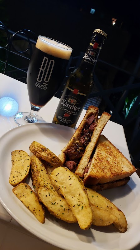 Hamburguesa jugosa de Mamá Juanita con queso fundido, papas fritas y una cerveza artesanal al lado, sobre una mesa de madera