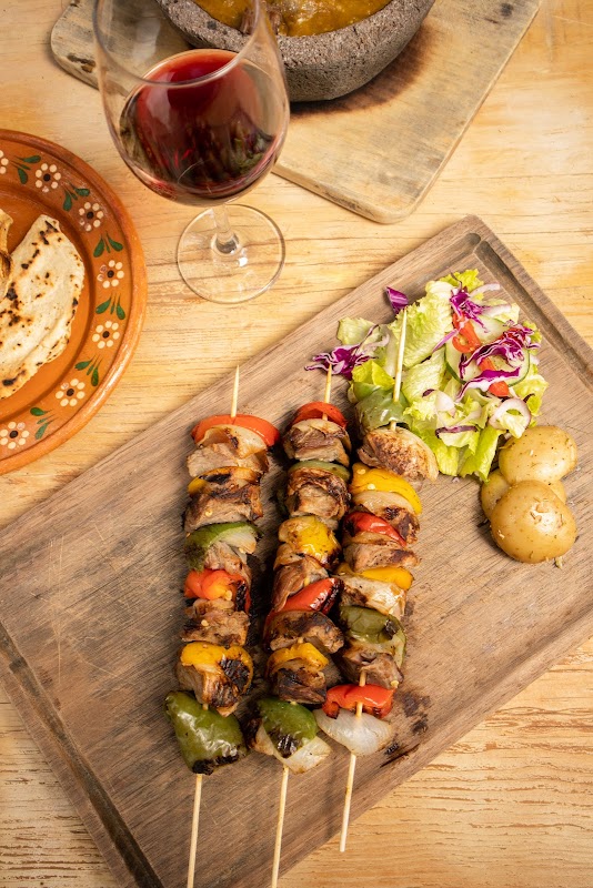 Parrilla encendida en Carnes Asadas Buenavista con tortillas de maíz y guacamole al lado de un plato de carne al carbón