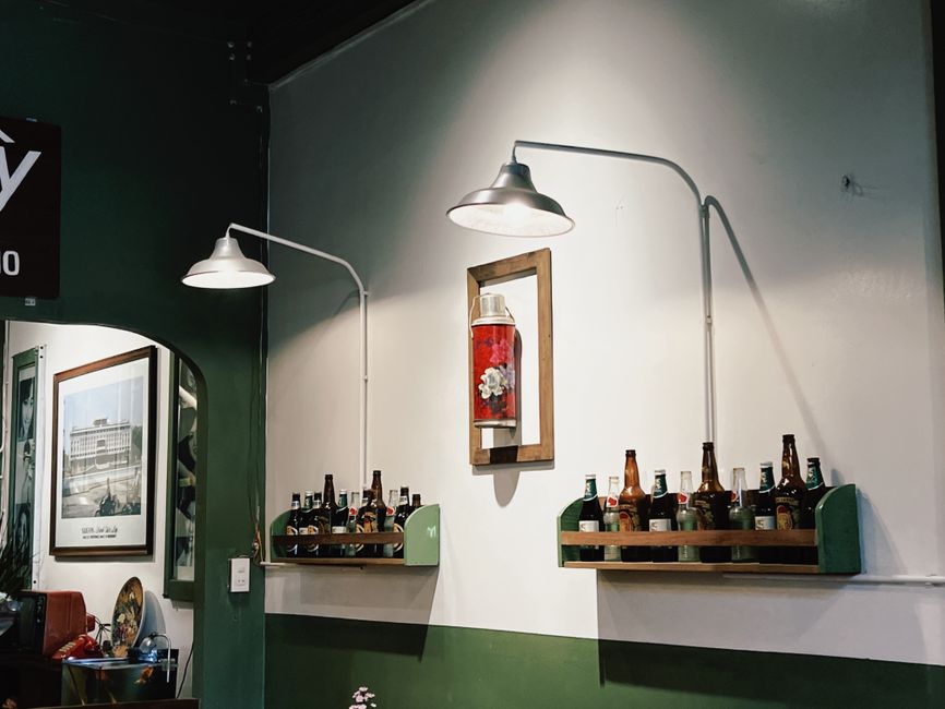 Warm and inviting cafe interior in Ben Tre, Vietnam with unique bottle decor and retro lighting.
