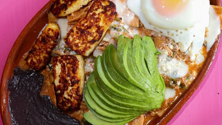 Mostrador de Chilaquiles Adelita con chilaquiles rojos y una jarra de agua fresca, interior colorido
