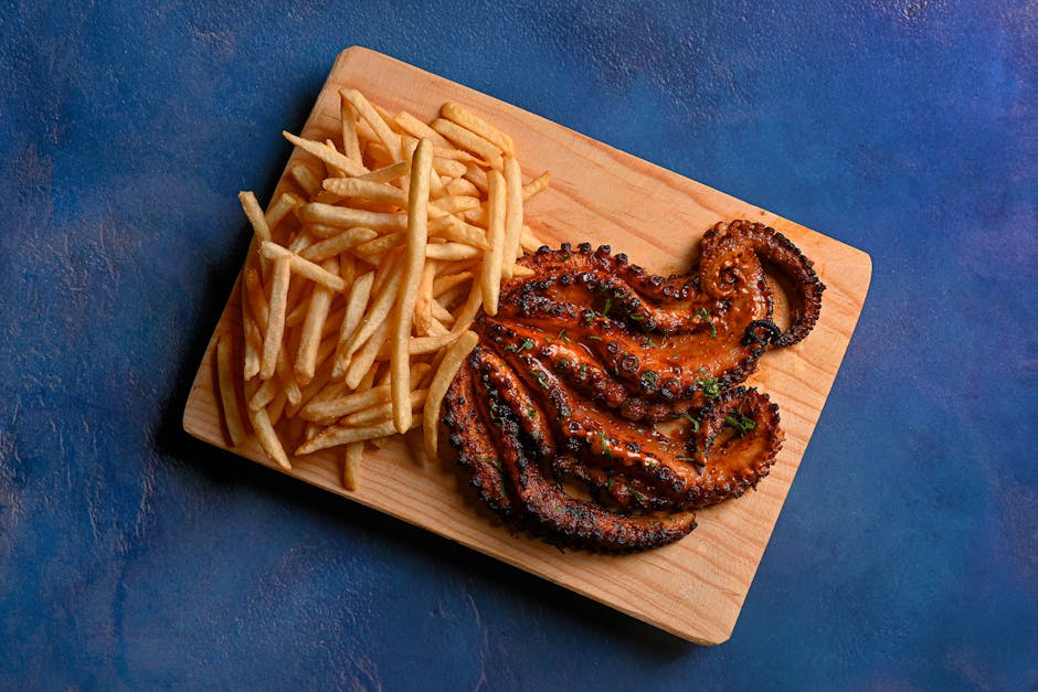 Delicious grilled octopus served with crispy French fries on a wooden board, perfect for seafood lovers.
