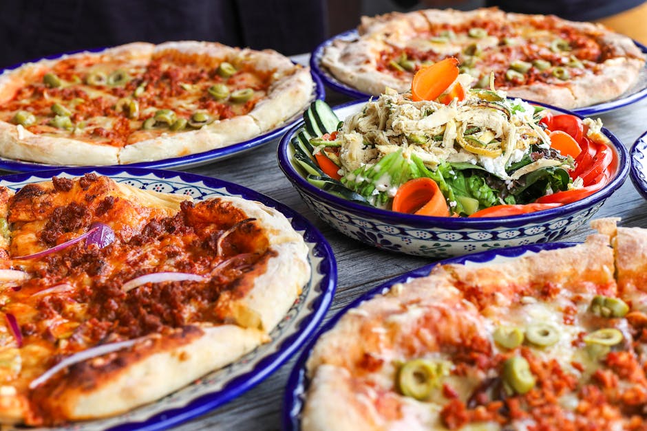 A vibrant set of various pizzas and a fresh salad bowl, perfect for a tasty meal.