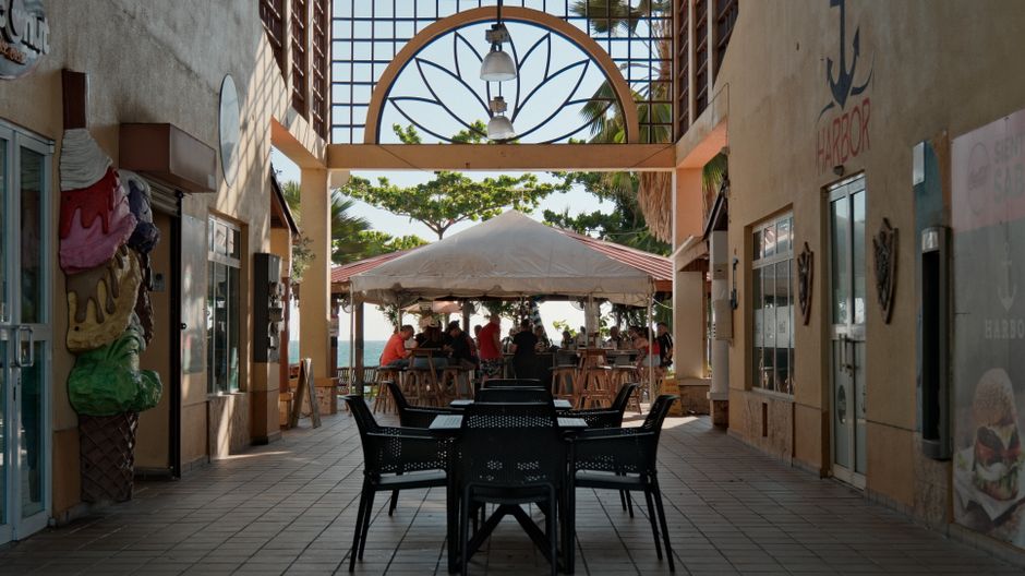 Scenic outdoor café with a tented dining area and sea view, surrounded by decorative elements.