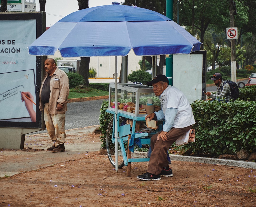 a man sitting on a blue chair under a blue umbrella