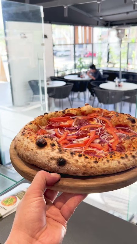 Pizza vegana de mozzarella de almendra en Marsala Pizza & Salads — horno de leña al fondo